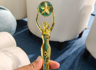 Gold trophy with a star on top held by a person, featuring the GAMA logo.