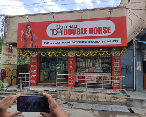 Tenali Double Horse store front with a person taking a photo with a phone.